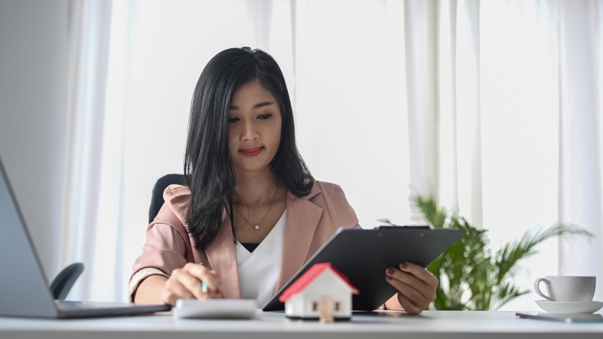 Focused real estate agent using calculator and working at office desk.